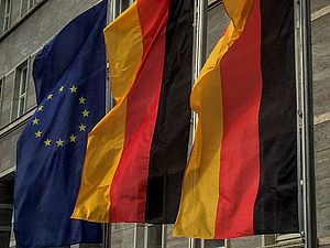 An drei Fahnenmasten wehen zwei deutsche und eine europäische Flagge