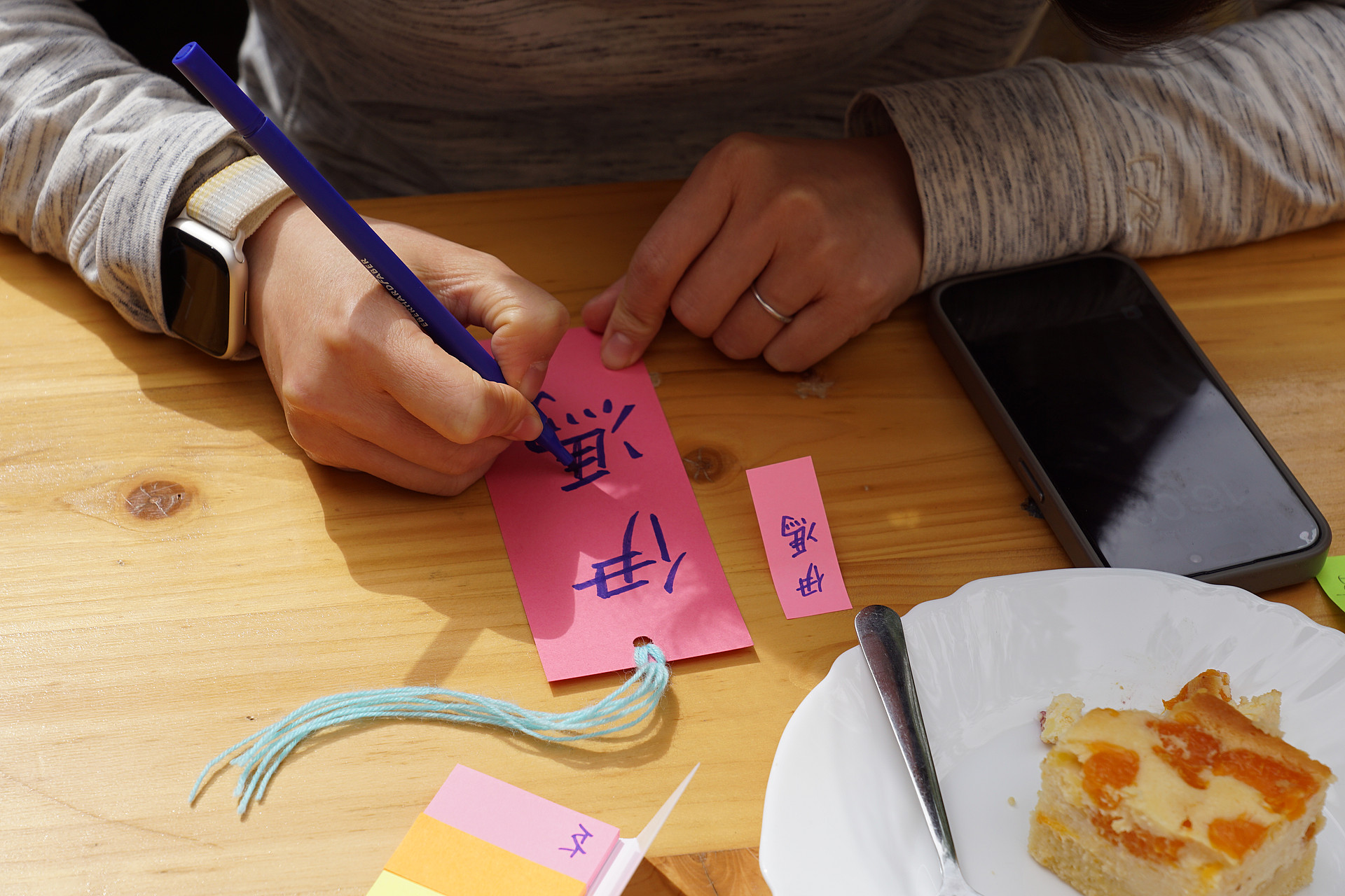 ein Name wird in chinesischen Schriftzeichen auf ein pinkes Lesezeichen geschrieben